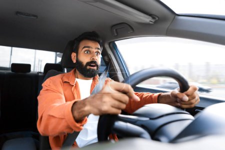 Téléchargez les photos : Le stress et le danger de conduire. Homme indien effrayé tenant volant regardant la route en état de choc, ayant une situation risquée d'accident de voiture lors de la conduite d'une nouvelle automobile. Concentration sélective - en image libre de droit
