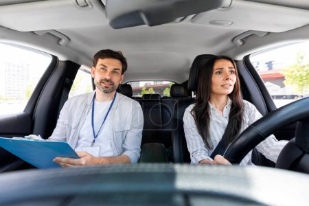 Photo for Unconfident millennial pretty woman driving car for first time with instructor handsome man giving her advices and tip. fear of driving concept. Scared lady attending driving school - Royalty Free Image