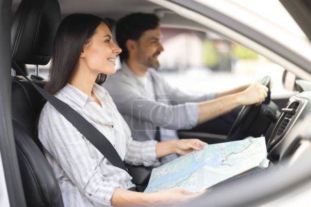 Photo for Cheerful millennial spouses friends travelling by car together. Happy smiling young man and woman couple enjoying road trip, looking at road, checking map, choosing destination to travel - Royalty Free Image