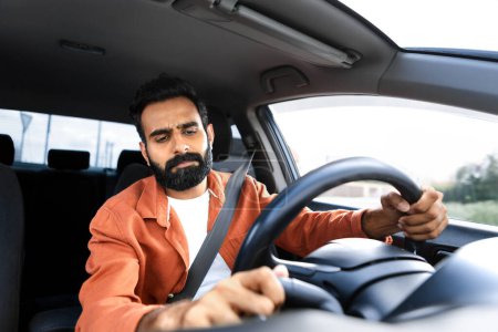 Photo for Vehicle Breakdown Problem. Displeased Middle Eastern Driver Man Having Issue With Automobile During Ride, Driving Car And Pushing Button On Dashboard. Discontented Guy Posing Inside His Auto - Royalty Free Image
