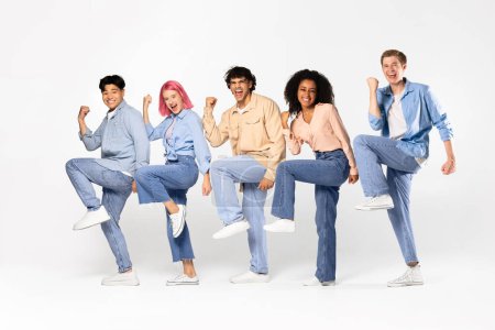 Photo for Yes. Overjoyed multiracial teen friends cheering and shaking clenched fists, celebrating win and good news standing isolated over white studio background, full length - Royalty Free Image