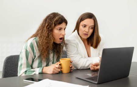 Photo for Two Coworkers Women Having Problem With Laptop, Looking At Shock On Computer Screen While Working At Office Table Together Indoor. Bad News, Internet Connection Issue At Workplace - Royalty Free Image
