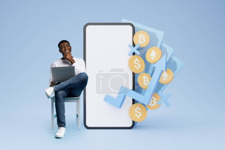 Photo for Cheerful young black man trader using laptop, sitting by huge phone with white blank screen, money cash 3d illustration on blue background. Trading on stock and markets online, mockup, blank space - Royalty Free Image