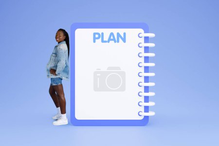 Photo for Smiling young black lady near large plan, with copy space, recommendation future planning for dream, isolated on pink studio background. Motivation and lifestyle, study and beauty care - Royalty Free Image