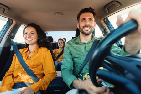 Foto de Jóvenes padres europeos e hija montando un coche nuevo y sonriendo, disfrutando de un viaje por carretera juntos. Familia teniendo vacaciones viajando juntos en auto - Imagen libre de derechos