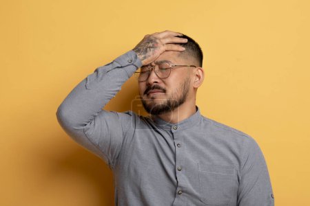 Photo for Young Asian Man Doing Facepalm Gesture While Standing Isolated Over Yellow Background, Portrait Of Disappointed Stressed Millennial Male Covering Face With Hand, Emotionally Reacting To Fail - Royalty Free Image