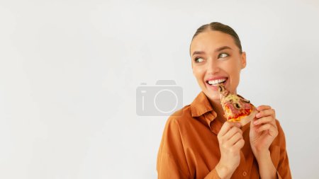 Photo for Happy woman eating slice of tasty italian pizza and looking back at free space for mockup advertisement on white studio wall background, banner panorama - Royalty Free Image