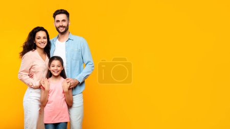 Glücklich liebende Familie. Europäische Mutter und Vater posieren mit ihrer Tochter isoliert auf gelbem Hintergrund, Panorama, freier Raum. Zusammenhalt und Bindungskonzept