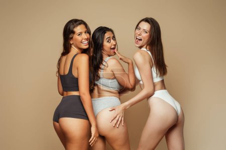 Photo for Laughing millennial different women in underwear with open mouth have fun, enjoy beauty care, isolated on beige background, studio. Self love, wellness and anti cellulite treatment, surgery - Royalty Free Image