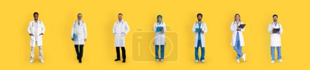 Photo for Cheerful adult, old diverse men and women doctors in white coats with tablets, isolated on yellow studio background, panorama. Professional work, help, medicine and health care - Royalty Free Image