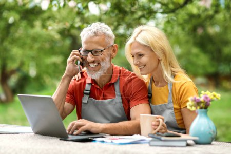 Photo for Business After Retirement. Smiling Senior Spouses Using Laptop And Talking On Cellphone While Sitting At Terrace Outdoors, Happy Older Couple Working Online, Managing Eco-Farming Company Together - Royalty Free Image