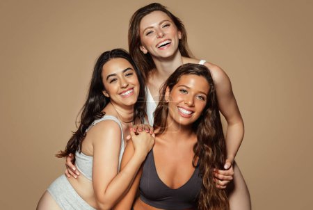 Photo for Glad millennial caucasian, latin, arab women in lingerie enjoy health, beauty care, isolated on beige background, studio. Natural perfect skin, spa treatments, wellness and different types - Royalty Free Image