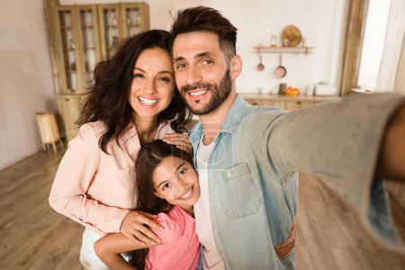 Photo for Family selfie. Happy father, mother and their daughter taking photo, loving parents and cute child girl posing and smiling at camera while bonding together at home - Royalty Free Image