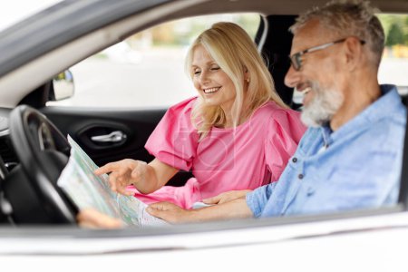 Photo for Happy retired couple friends travelling together by car. Cheerful excited senior man and woman sitting at auto front seat, checking map, choosing destination to travel. Holiday, family weekend - Royalty Free Image