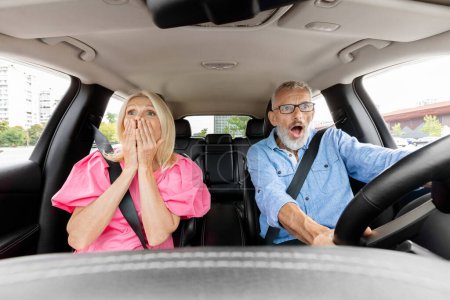 Photo for Shocked caucasian senior couple in automobile looking at road with terrifying face expression, having risk of car accident during ride. View from auto dashboard. Stressful traffic - Royalty Free Image