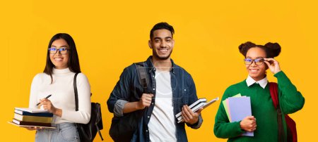 Photo for Education Concept. Collage With Happy Multiethnic Students With Backpacks And Workbooks Posing Isolated Over Yellow Studio Background, Diverse Young College Friends Smiling At Camera, Panorama - Royalty Free Image