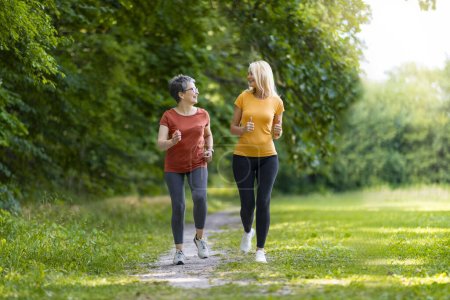 Photo for Two Sporty Senior Woman Jogging Together In Park, Happy Older Ladies Running Outdoors, Mature Friends Training Outside, Enjoying Active Lifestyle, Full Length Shot With Copy Space - Royalty Free Image