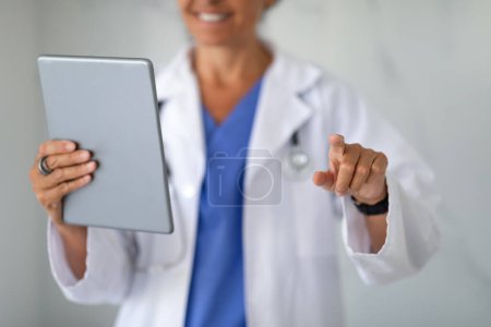 Foto de Tecnologías modernas en concepto de salud. Recortado de mujer médico con tableta digital en la mano tocando espacio en blanco, comprobando los datos del paciente en línea. Técnicos médicos - Imagen libre de derechos