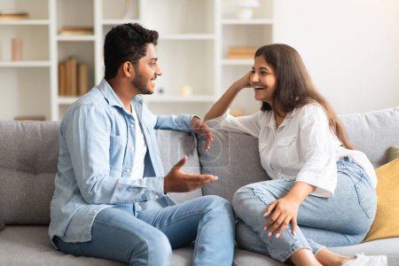 Téléchargez les photos : Jeune couple indien aimant parler et flirter profiter de la conversation à la maison, passer du temps ensemble assis sur le canapé. Mariage heureux et concept de relation romantique - en image libre de droit