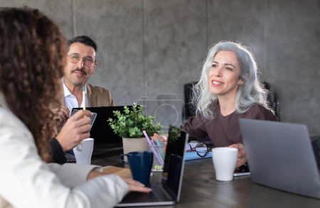 Photo for Teamwork. Business professionals actively participating in meeting discussion of strategy, exchanging ideas sitting at table in modern office office. Colleagues collaboration. Selective focus - Royalty Free Image