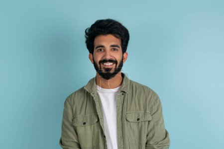 Photo for Cheerful positive handsome millennial indian guy in stylish casual outfit posing isolated on blue studio background, smiling at camera, copy space. Millennials lifestyle, people concept - Royalty Free Image