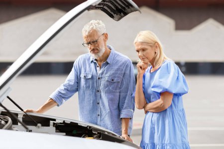 Photo for Upset concerned senior couple man and woman wearing casual outfit have road trip, elderly spouses experience problems because of breakdown engine, old man checking auto motor - Royalty Free Image