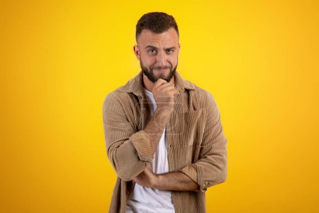 Photo for Cheerful pensive cunning millennial caucasian guy with beard in casual thinks, isolated on yellow studio background. Flirt, lifestyle and human emotions, ad and offer for work - Royalty Free Image