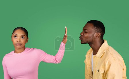 Téléchargez les photos : Jeune couple deux amis noir homme et femme sur fond vert. Guy essayer veulent embrasser dame, mais elle arrête geste de la paume et ne veut pas. Zone d'amis, amitié, concept de relations - en image libre de droit