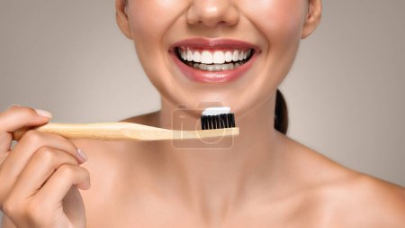 Téléchargez les photos : Souriant jeune femme européenne brossant les dents avec une brosse, profiter des procédures de routine le matin, isolé sur fond de studio gris, panorama, recadré. Soins buccodentaires, caries, hygiène et dentisterie - en image libre de droit