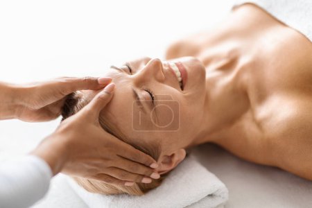 Photo for Portrait of relaxed middle aged woman having comforting acupressure head massage, enhancing tranquility and mental calm, smiling mature lady getting wellness treatment an upscale spa salon - Royalty Free Image