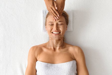 Photo for Beautiful middle aged woman relaxing during acupressure head massage at luxury spa salon, top view shot of attractive mature lady experiencing peaceful moments while getting wellness treatment - Royalty Free Image