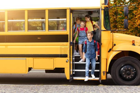 Foto de Grupo de niños alegres bajando del autobús escolar amarillo, niños sonrientes dejando el vehículo, sus rostros brillantes con felicidad y anticipación para un día de aprendizaje y diversión, espacio para copiar - Imagen libre de derechos