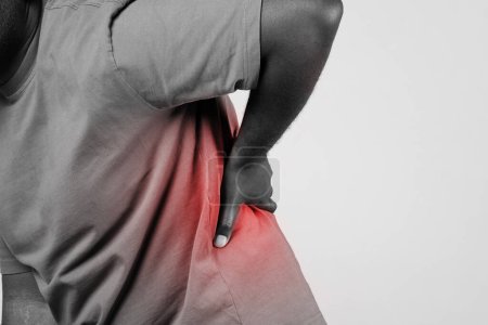 Photo for Cropped shot of african american guy touching aching lower back with red pain spot over studio background. Strain or injury, physical health issue concept. Black and white - Royalty Free Image