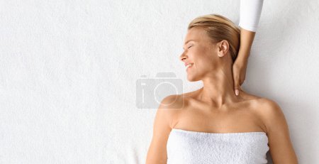 Photo for Wellness Concept. Beautiful middle aged woman getting relaxing neck massage, attractive mature lady embodying serene leisure and pampering in luxury spa salon, top view shot with copy space, panorama - Royalty Free Image