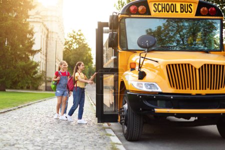 Foto de Grupo de niños felices abordando un autobús escolar amarillo después de las clases, alumnos alegres con mochilas entrando en el vehículo, grupo de niños riendo y sonriendo, listos para ir a casa, espacio para copiar - Imagen libre de derechos