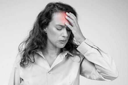 Photo for Despaired european young lady, with pained expression, clutch forehead, red inflamed, suffer from headache. Work, suggesting stress, migraine, health problems, isolated on black, white background - Royalty Free Image