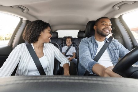 Photo for Joyful black family enjoying car ride by their new auto. Happy african american mother, father and preteen kid son sitting inside new automobile, have conversation, going vacation together - Royalty Free Image