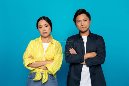 Photo for Offended sad bored tired millennial asian family in casual crossed arms on chest, after quarrel, isolated on blue studio background. Emotions, relationship problems, bad mood - Royalty Free Image