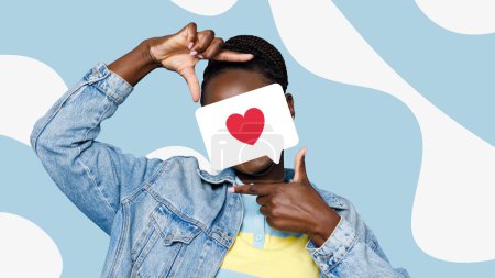 Photo for Stylish black woman covers her face with heart speech bubble card while making frame with fingers against light blue backdrop with abstract white shapes - Royalty Free Image