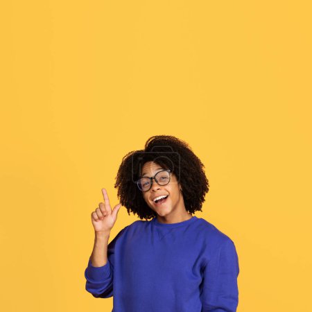 Photo for Idea Concept. Excited Young Black Guy Pointing Finger Up And Looking At Camera, Happy African American Man In Eyeglasses Found Problem Solution, Having Inspiration, Posing On Yellow Studio Background - Royalty Free Image