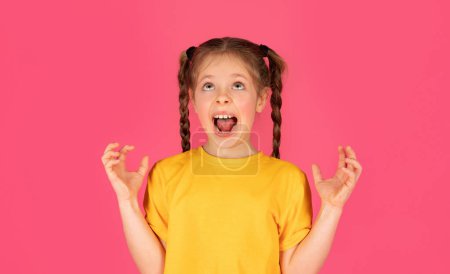 Foto de Retrato de niña estresada gritando fuerte en el estudio, niño preadolescente emocional enojado gritando y mirando hacia arriba, teniendo colapso mental, de pie aislado sobre el fondo rosa, espacio de copia - Imagen libre de derechos