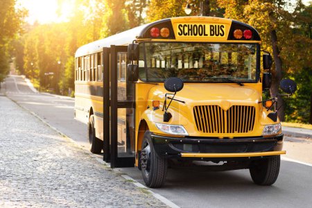 Photo for Transportation Services Concept. Front Shot Of Parked Retro Yellow School Bus With Stop Sign Standing On The Road, Empty Schoolbus With Opened Doors Waiting For Pupils On Parking Lot, Copy Space - Royalty Free Image