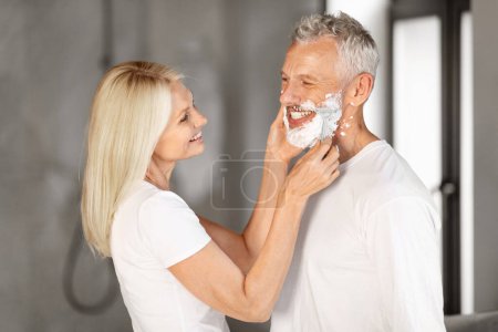 Photo for Caring Happy Mature Woman Helping Her Husband With Shaving Face While They Making Morning Hygiene In Bathroom, Happy Senior Couple Having Fun While Getting Ready Together, Closeup Shot - Royalty Free Image