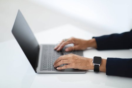 Téléchargez les photos : Gros plan de femme d'affaires d'âge moyen méconnaissable travaillant sur un ordinateur portable, les mains tapant sur le clavier de l'ordinateur tout en travaillant dans le bureau, vue de côté, image recadrée - en image libre de droit