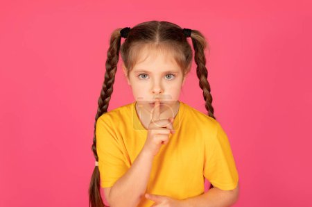 Photo for Keep Silence. Portrait Of Little Girl Showing Shh Gesture At Camera, Preteen Female Child Holding Finger Near Lips, Gesturing Hush While Standing Over Pink Studio Background, Copy Space - Royalty Free Image