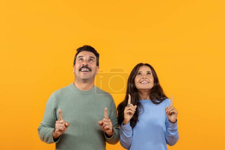 Photo for Shocked senior caucasian couple in casual point finger up at copy space, isolated on orange studio background. Surprise, relationships and idea, ad and offer, attention sale - Royalty Free Image
