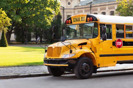 Foto de Gran autobús escolar amarillo se detuvo en una carretera con su señal de stop rojo, autobús escolar sin pasajeros de pie en la calle tranquila, esperando a los niños, vehículo retro listo para recoger a los estudiantes después de las lecciones - Imagen libre de derechos