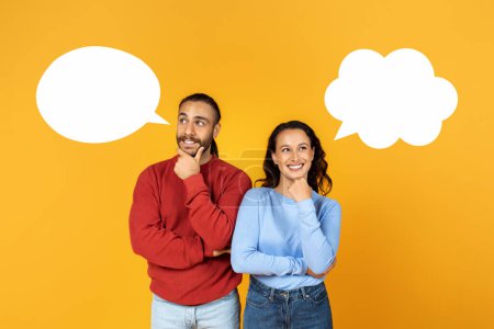 Photo for Millennial couple with empty speech bubbles next to their heads on yellow studio background, mockup for design. Attractive pensive young guy and his girlfriend with blank word clouds - Royalty Free Image
