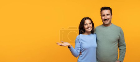 Photo for Smiling senior caucasian lady in casual hug man, hold on hand free space, isolated on orange studio background. Lifestyle family, relationships and love, ad and offer recommendation - Royalty Free Image