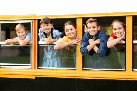 Foto de Niños alegres mirando desde la ventana de su autobús escolar, alumnos alegres sonriendo a la cámara, yendo a casa después de clases, alumnos entusiastas listos para el próximo viaje y aventura, espacio para copiar - Imagen libre de derechos
